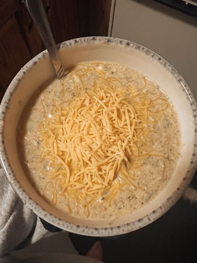 bowl of broccoli cheddar soup with cheese on top 