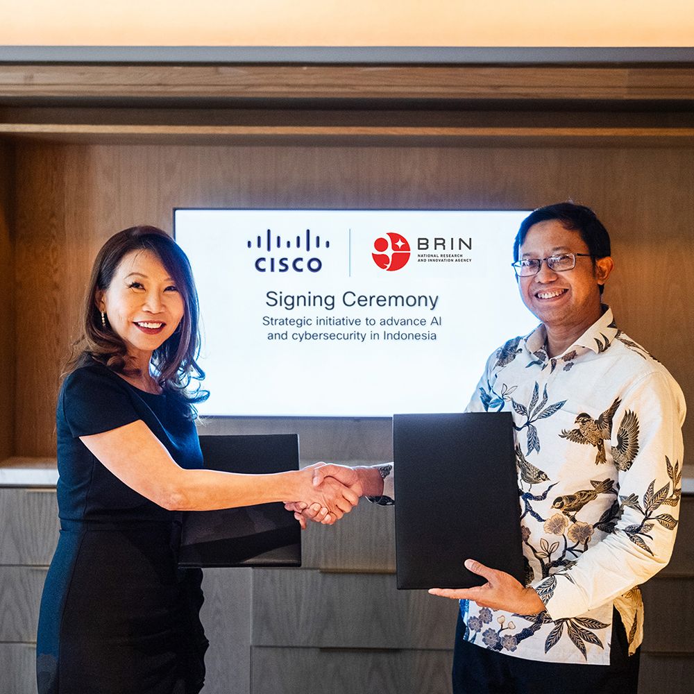 A picture of two people shaking hands in front of a signing ceremony sign
