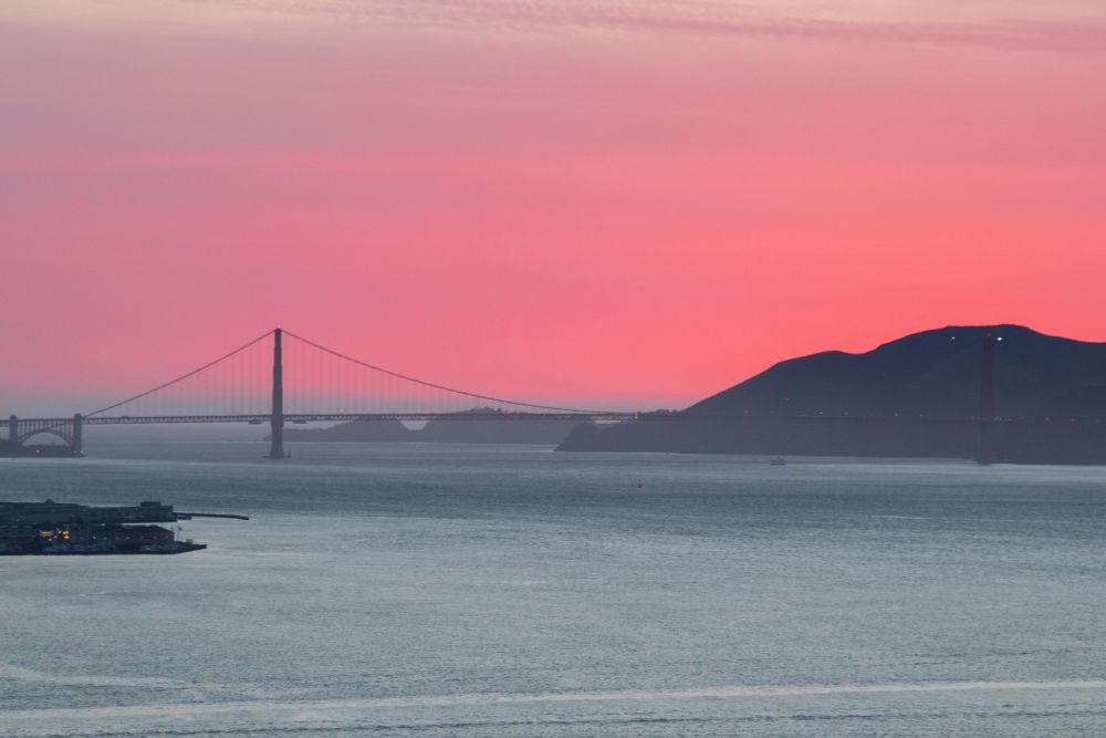 A sunset landscape showing the golden gate bridge against the pacific ocean