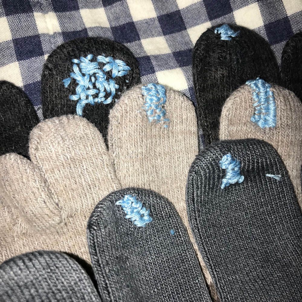 三足分の五本指靴下の親指が水色の糸で乱雑に繕われている。靴下は黒、ライトグレー、チャコールグレー。