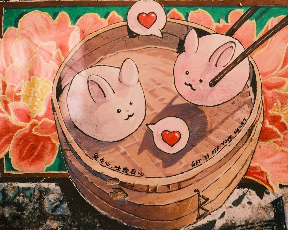 Warm-toned photo of a mural in Ipoh, Malaysia, featuring two dumplings that look like smiling bunnies.