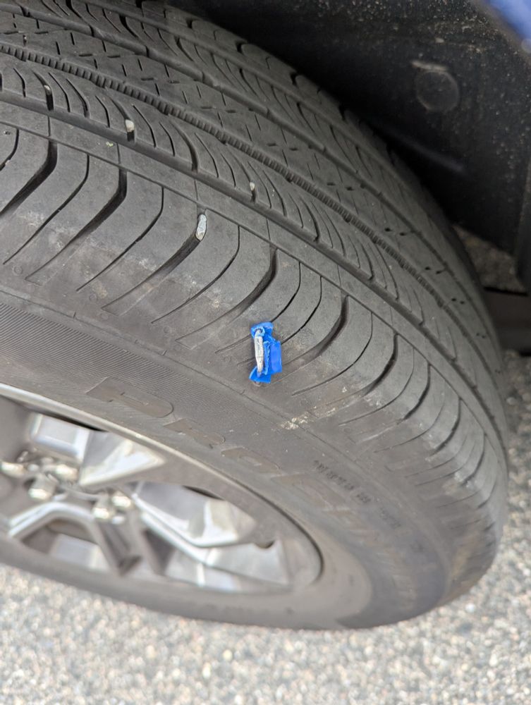 Picture of a soon to be flat tire with a staple in the sidewall