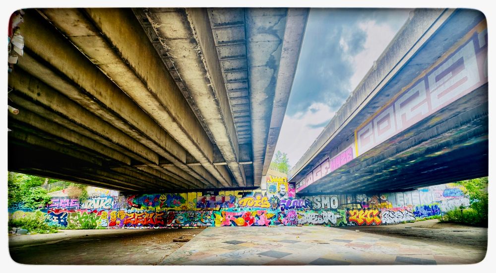 View from beneath an underpass with graffiti and sky 