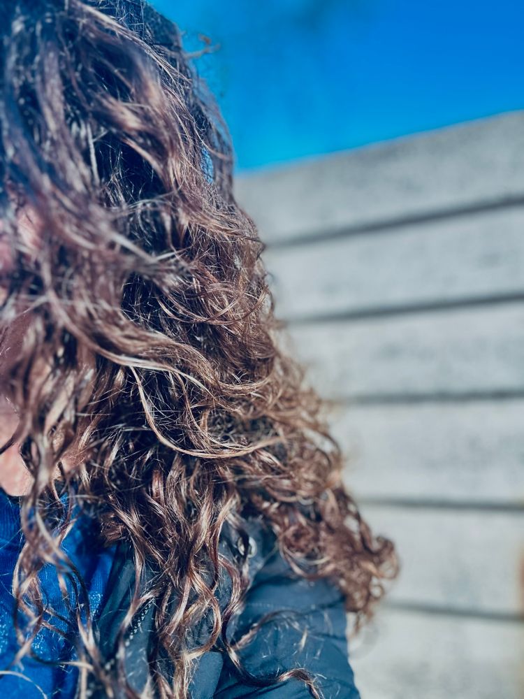 Side on of a woman with curly hair with brown and gold highlights and blue coat and jumper and a breeze block wall and blue sky behind her 

From low by Nick Flynn

‘as if the horse had never been ridden

/

They say a horse is broken when the rider
can stay on

they say the past is broken when you can
let go of it

I have broken with the past, she says

I have erased it from my phone
I have blindered my eyes from her eyes

/

I didn’t know the past was made of horses
I didn’t even call it a horse until now

I didn’t even call it strange
until I looked back on it

the past was a horse crossing a desert
a body draped over it

this is how we get the beloved home

/

Strange now to never hear a horse upon waking
or when out in the field

I didn’t know the past would come for me
I didn’t even call it the past until now

sometimes one gallops past
but no one else ever sees it’