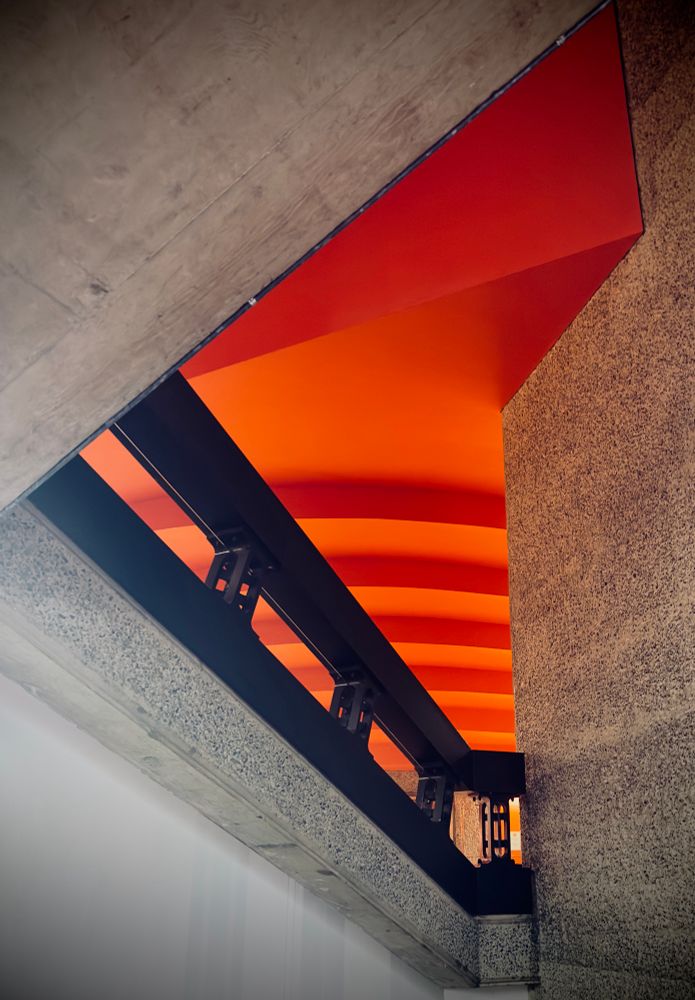 A red ceiling on a black staircase with concrete surrounding 
