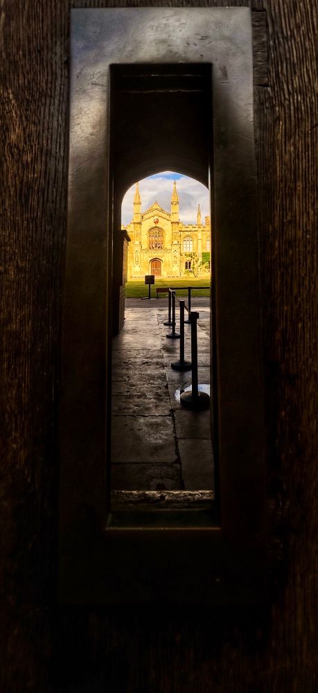 Opening in a door revealing a Cambridge jniversity and blue sky 