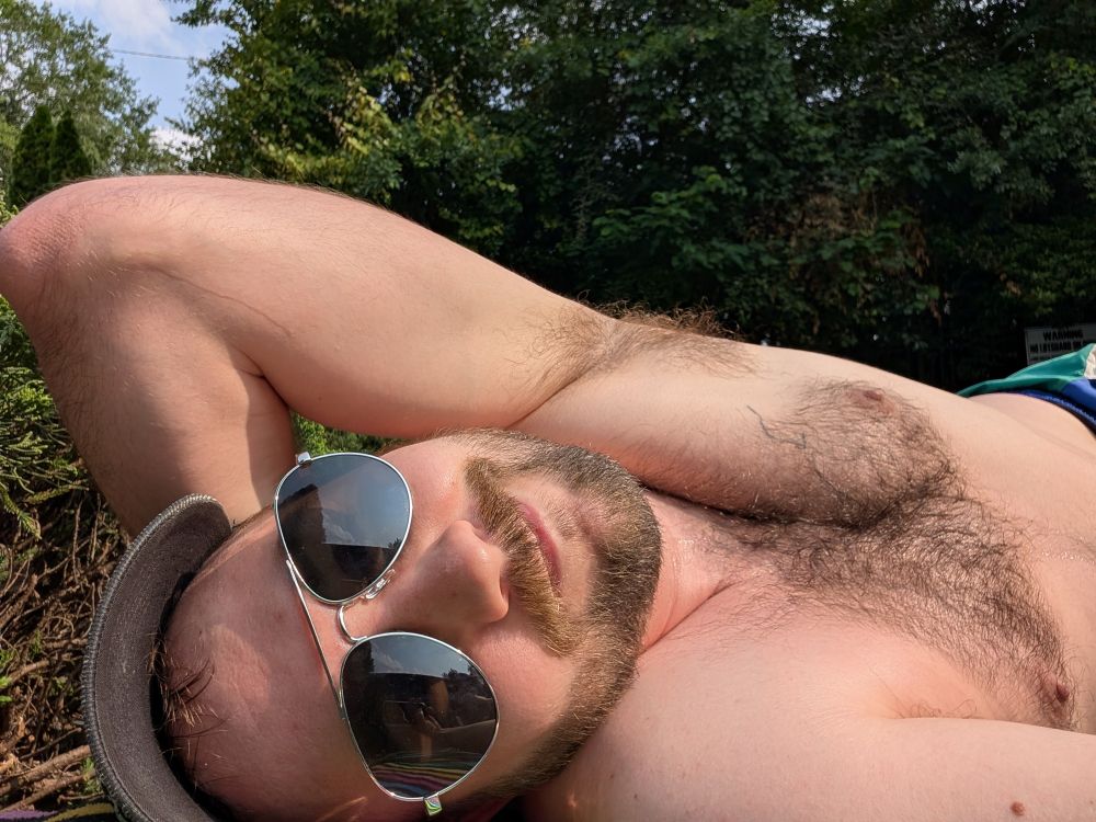 Rob, laying out shirtless and wearing sunglasses. His left armpit is in the air