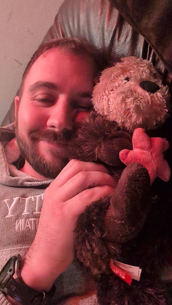 Rob, cuddling on a leather recliner with a toy stuffed otter