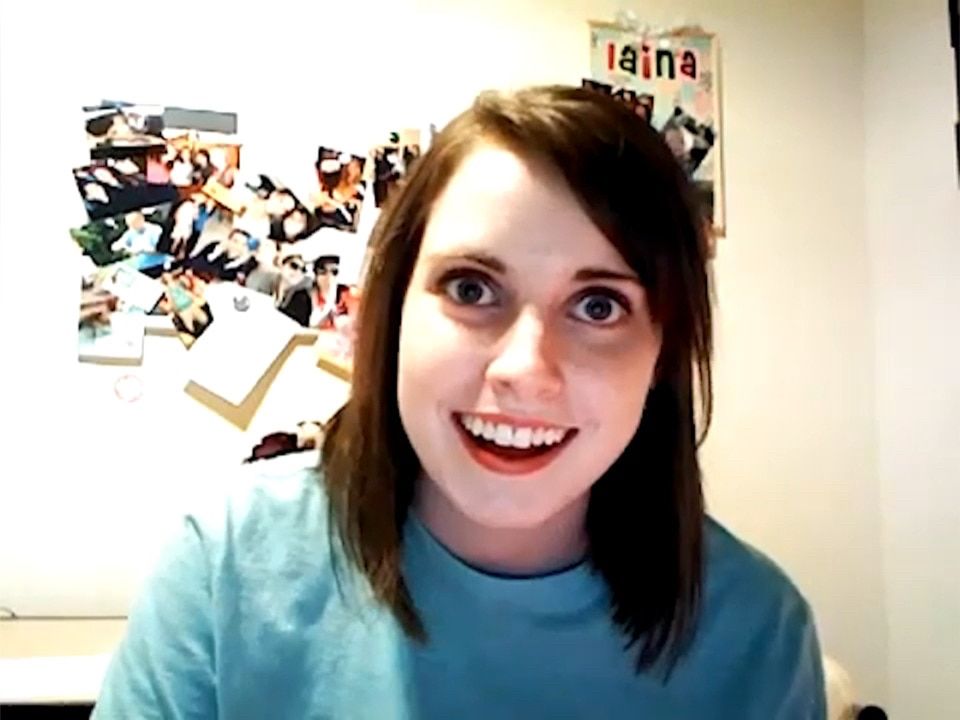 A girl with brown hair and light skin is wearing a celeste t-shirt. She’s staring at the camera with a wide smile, making her look like she’s a bit unhinged.