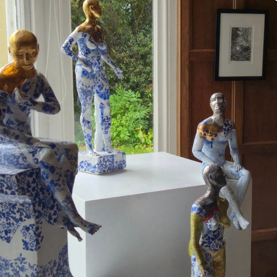 A selection of ceramic sculptures and a monochrome print in the wood-panelled drawing room of a country house.