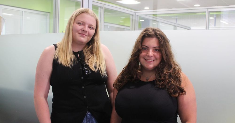 Two smiling students in an office.