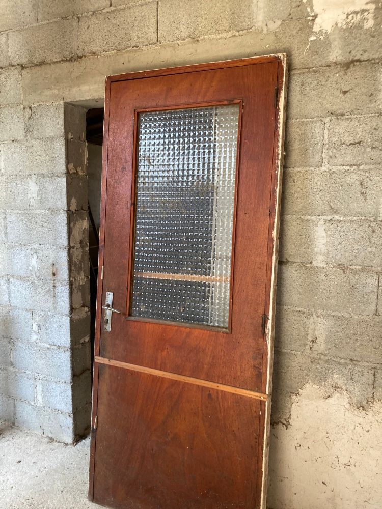 Mur en parpaing et porte marron avec une vitre 