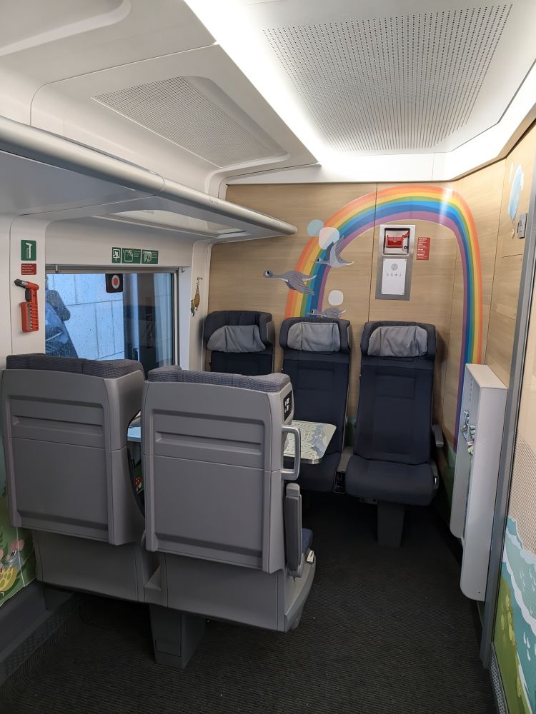 Blick auf die rechte Seite des Kleinkindabteils, mit fünf Sitzplätzen um einen Tisch.