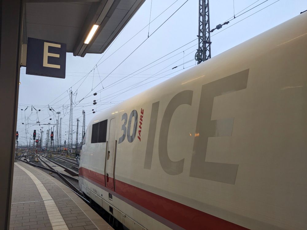 Triebkopf eines ICE 1 von schräg hinten an einem Bahnsteig. Auf dem Triebkopf ist groß der Schriftzug "ICE", links daneben ist ein kleinerer Schriftzug "30 Jahre", wo bei das Wort "Jahre" senkrecht geschrieben ist, so dass es aus der Ferne wie ein "I" aussieht.