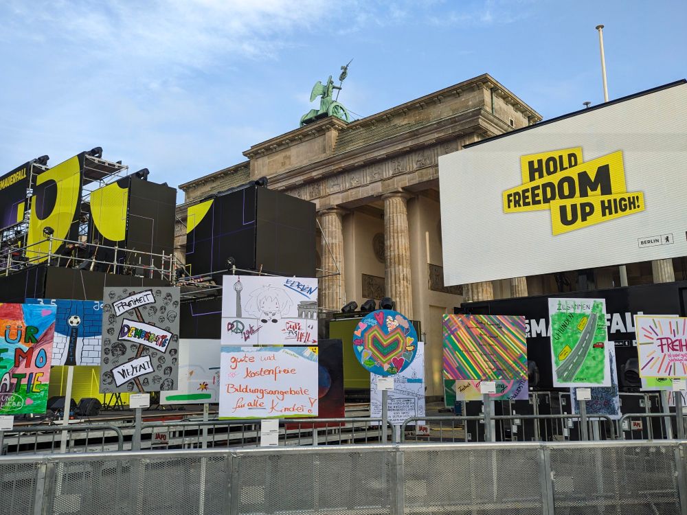 Eine Kunstinstallation zum Gedenken an den Mauerfall, im Hintergrund mittig das Brandenburger Tor, im Hintergrund links eine Bühne.