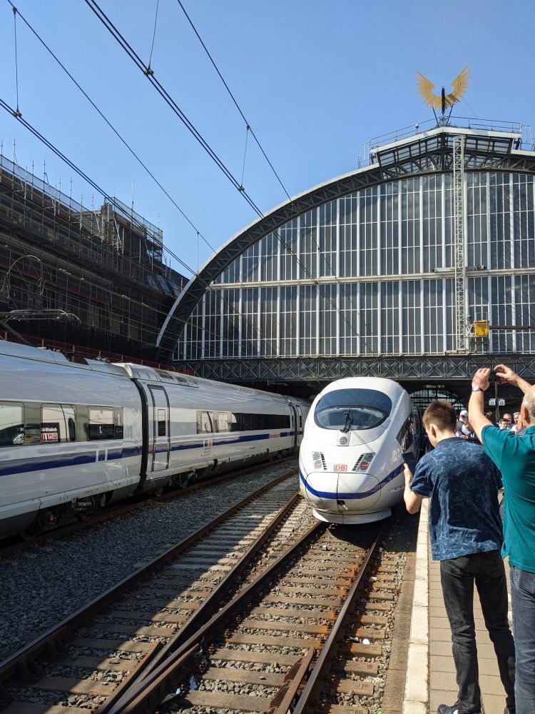 Blick vom Bahnsteig in Amsterdam Centraal. Auf der rechten Seite steht ein Zug der Baureihe 406 mit blauem Zierstreifen. Auf der linken Seite steht ein Zug der Baureihe 408 mit blauem Zierstreifen.