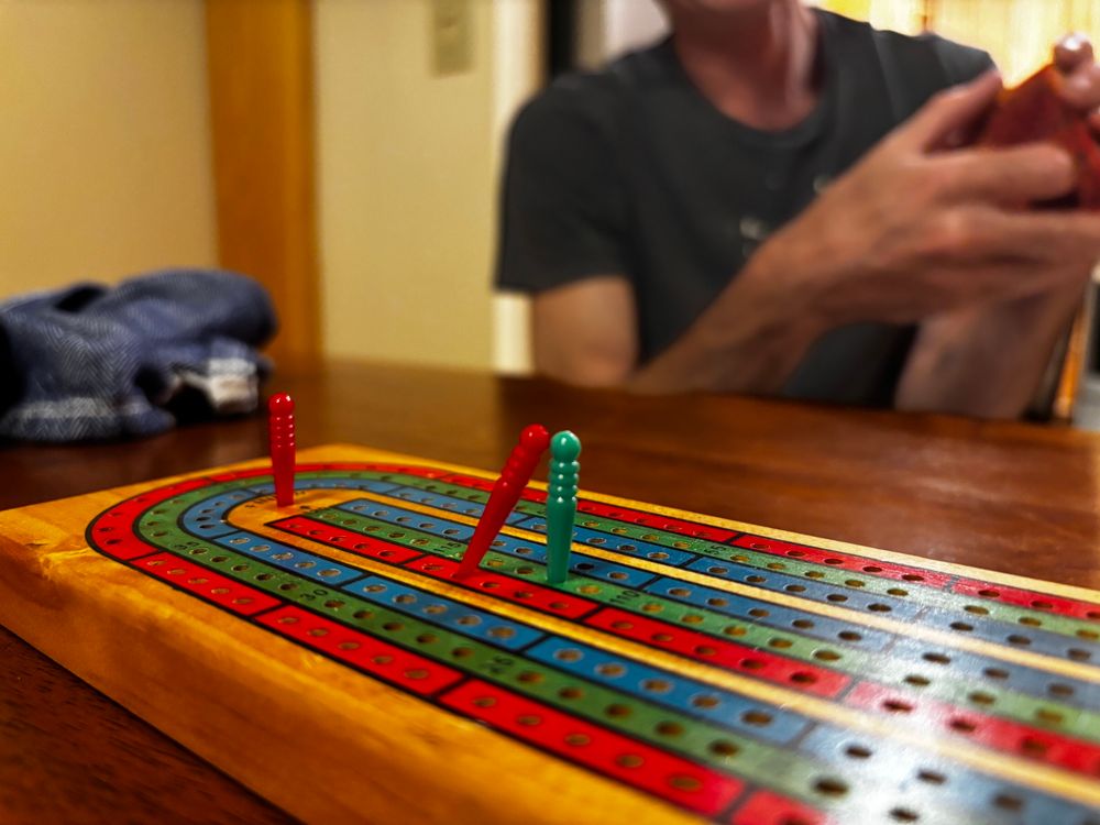 Cribbages board. Winning player’s peg is in the final spot while their other peg stayed behind to give a kiss to the losing player’s peg. 