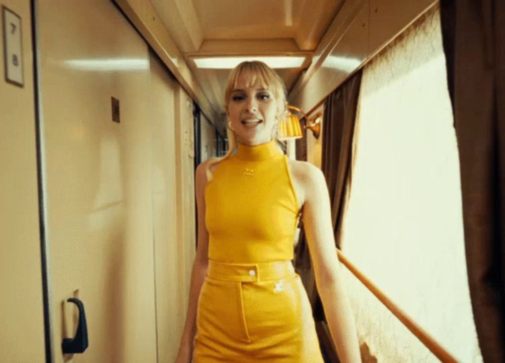 a woman in a yellow dress is walking down a hallway with the letter p on the wall