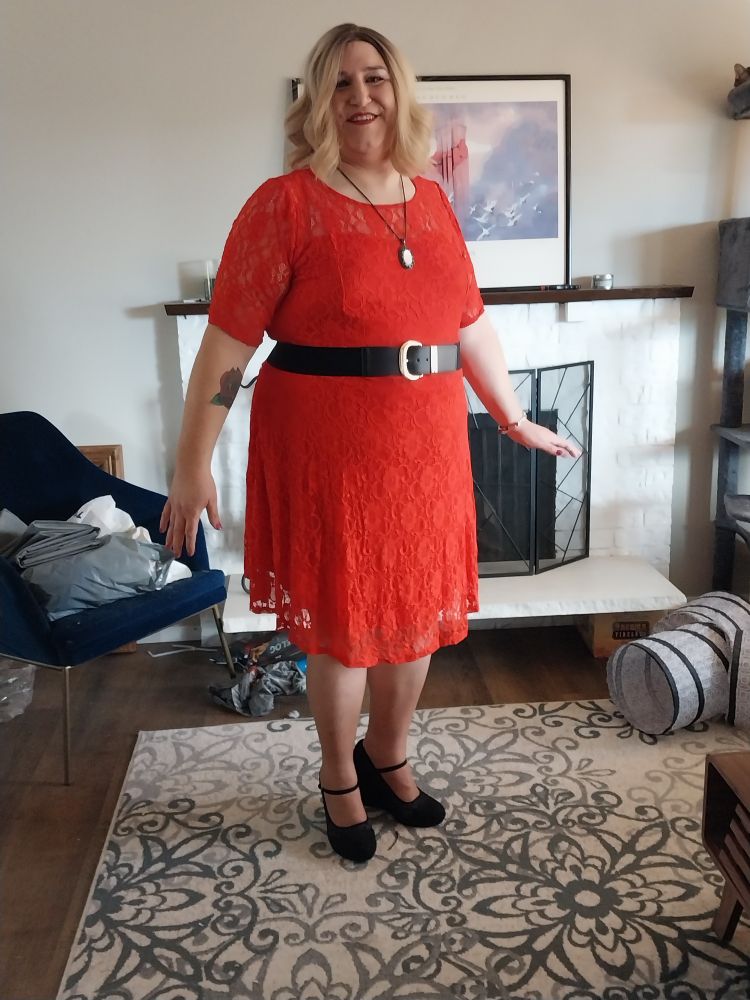 Eva in her blond wig wearing a knee length red lace dress, black belt, and 4.5" black wedges