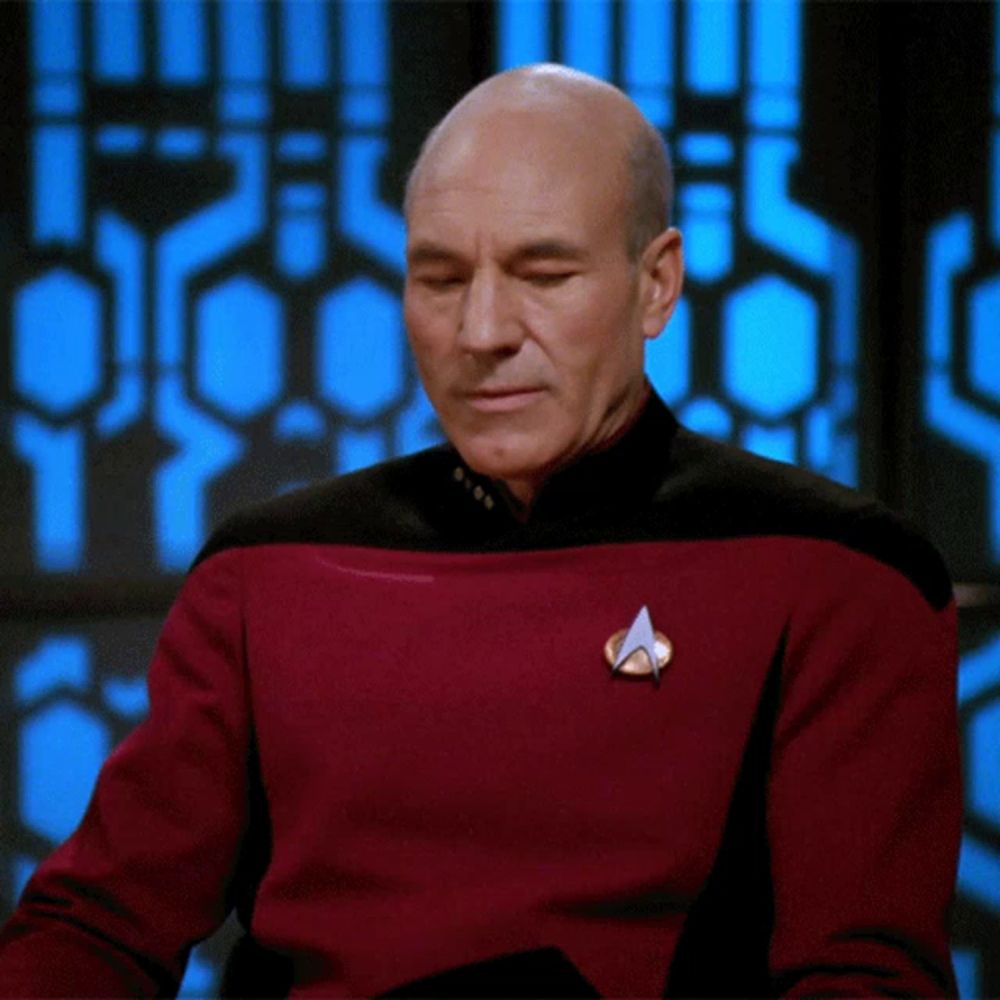 a bald man wearing a red sweater with a star trek logo on his chest