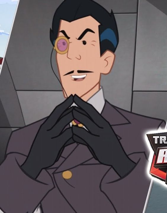 A white guy with black hair and pencil mustache in a dark gray suit with a broach and a monocle. He's touching the fingertips of his gloved hands in front of him. 