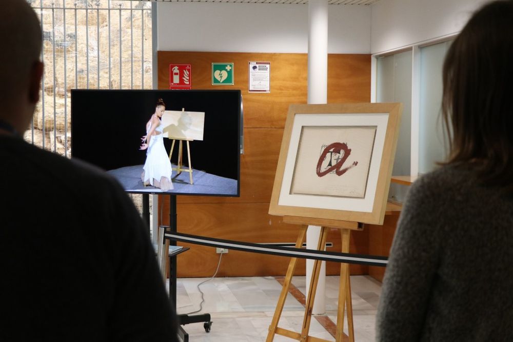 El quadre original de Tàpies amb el logotip i el vídeo artístic, exposats al vestíbul de l'edifici del Rectorat de la Universitat Rovira i Virgili.