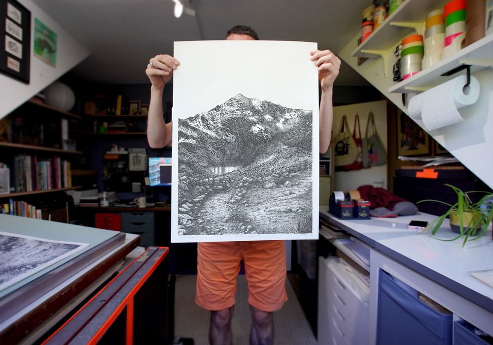 Designer and print maker Graham Pilling (Army of Cats Creative Studio) holds up his screen print of Snowdon / Yr Wyddfa in his studio room.
