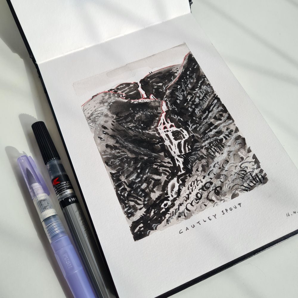 Ink and wash sketch of Cautley Spout, a waterfall in Sedbergh, by artist Graham Pilling. Alongside the sketchbook are the pens that were used and the sun is shining in a pleasant way. :)