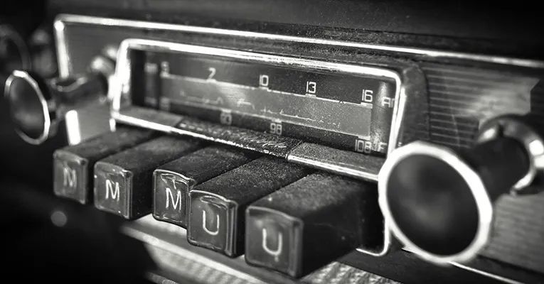 A photo of an old radio with large buttons that stick out and one is pushed in 