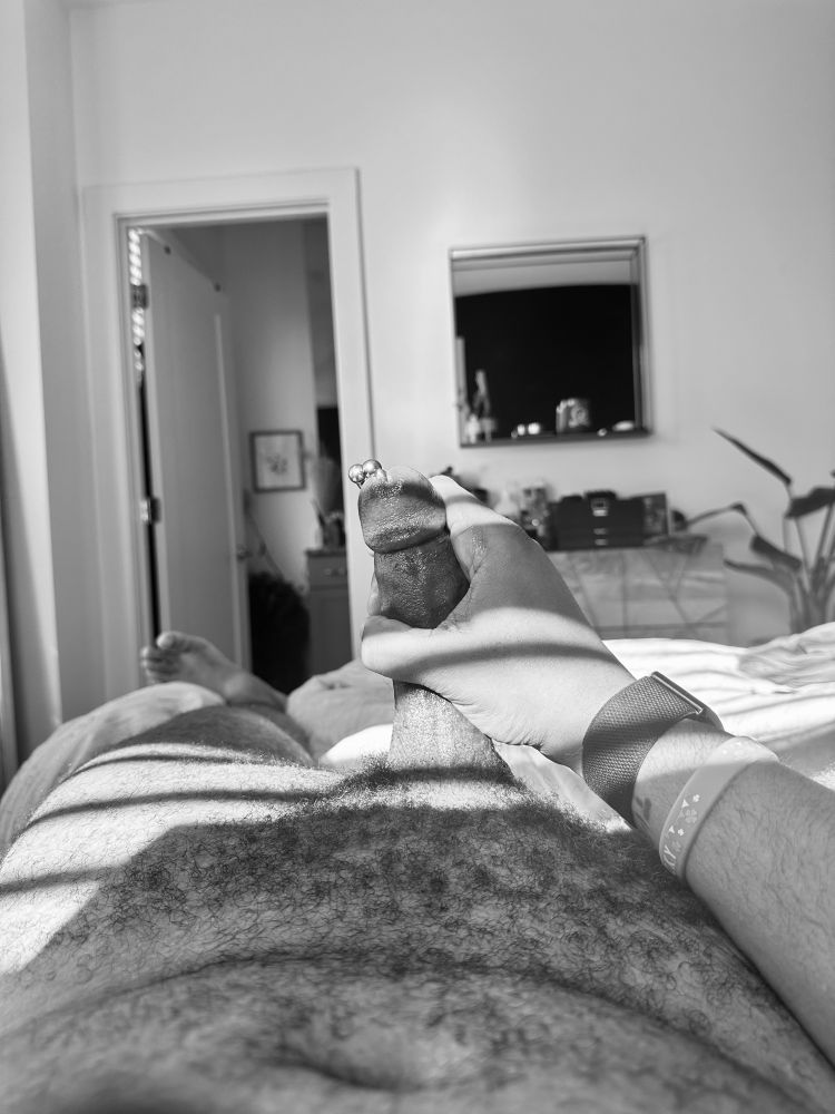 A black and white photo of my penis erect with a 2g Prince Albert horseshoe ring being lit by the sun coming through the window