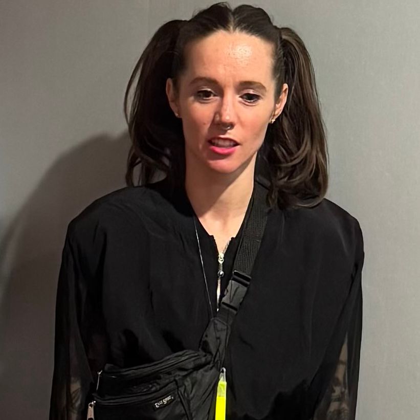 image of permanentviolet taken by @datarich.bsky.social. fem presenting person with brown hair wearing a black top disassociates while gazing into the middle distance.