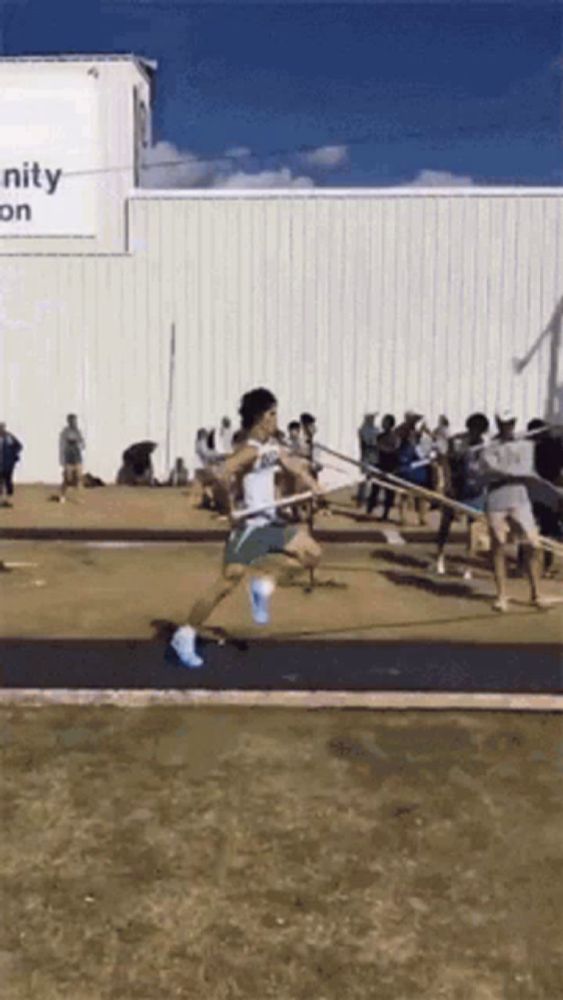 a man is jumping over a hurdle in front of a sign that says community on it