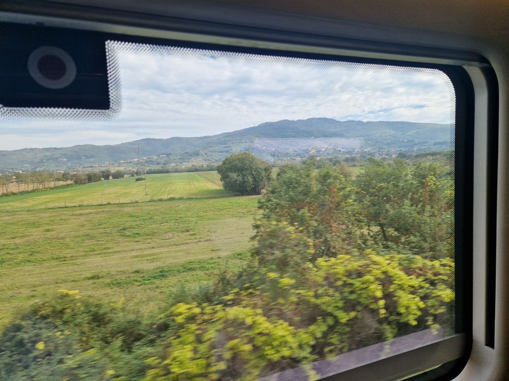 An Italian countryside view framed by a train window.