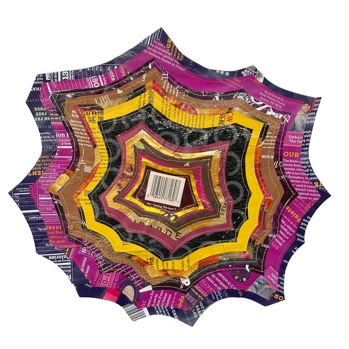 A photo of a piece of art. It is made of concentric layers of brightly colored plastics that have been cut into a sort of starburst shape and stitched together.