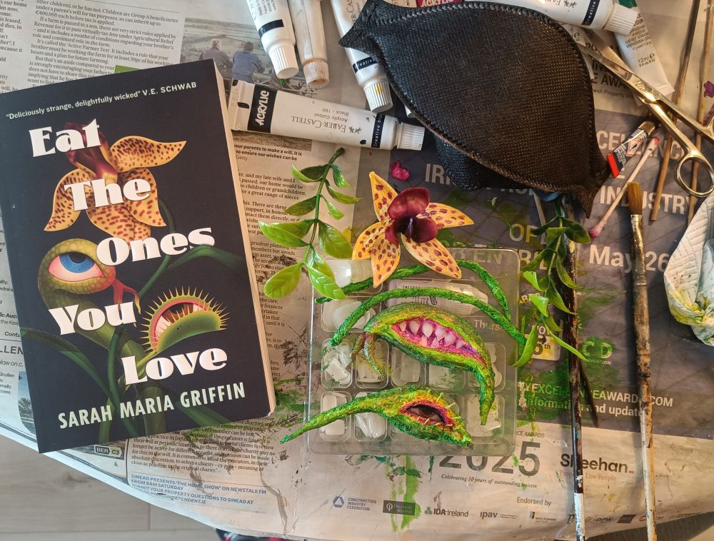 The prosthetics in progress on my workspace, beside the book cover of Eat The Ones You Love which I'm basing the designs on. 