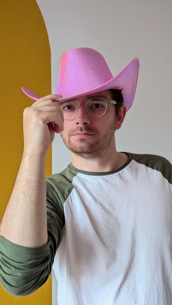 ItsJabo (white man) wearing a sparkly pink cowboy hat, tipping the front down with his right hand. 