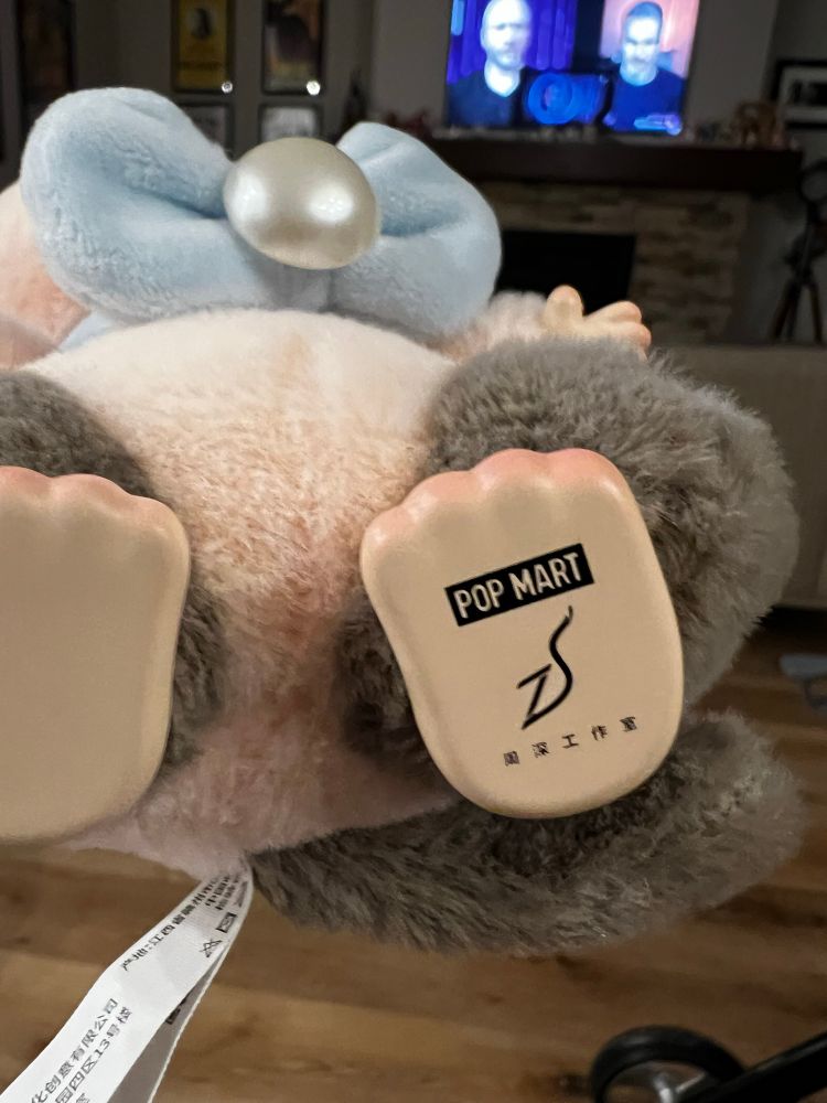 The bottom of a foot on a Pop Mart Zhou Shen plush vinyl pendant, with “Pop Mart” at the top and “ZS” below that. 
