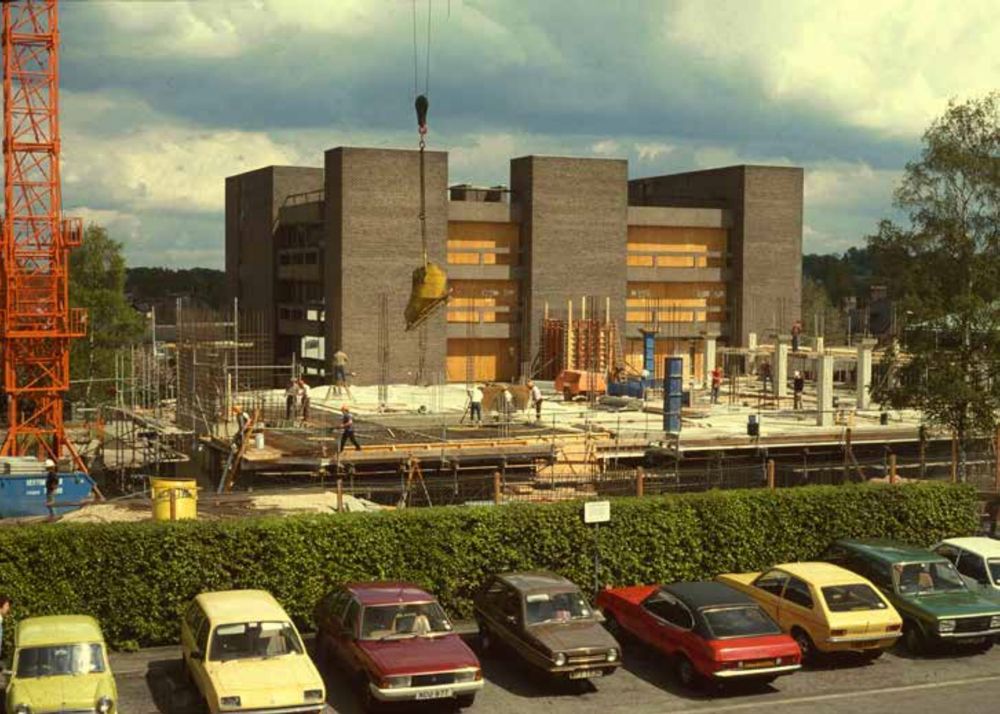 Library building under construction with parked cars in the foreground