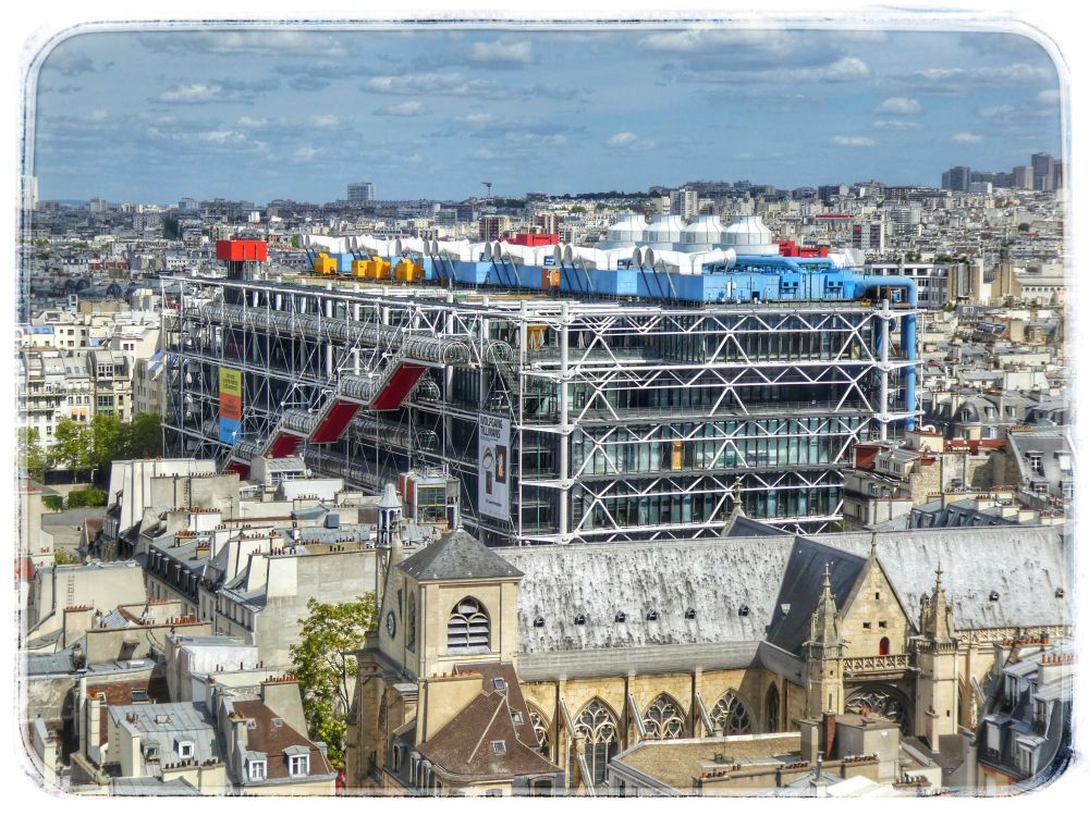 The image showcases an aerial view of the cityscape in Paris, France, dominated by the modern architectural structured museum Centre Pompidou juxtaposed with traditional Parisian buildings. The primary focus is on the Centre Pompidou, a distinctive building with its external framework of white supports, red staircases, and colorful pipes and equipment on the roof. The building's facade is primarily glass, allowing glimpses into its interior. Large banners hang on the exterior, adding vertical color elements.

The surrounding cityscape is a dense collection of buildings, primarily in muted tones of gray and beige, with various roof styles. A prominent church with a traditional architectural design, featuring pointed arches and a bell tower, is visible in the foreground. The composition is further enriched by a vast expanse of rooftops, creating a layered effect that suggests a sprawling urban landscape.

The color palette is dominated by neutral tones of gray, white, and beige, with pops of vibrant colors like red, yellow, and blue on the Centre Pompidou. The sky is a light blue with scattered white clouds, adding a soft background to the scene. The overall composition is a balance between the modern and the traditional, creating a visual interplay of architectural styles. The image has a slightly softened, vintage effect, adding to its aesthetic appeal.
