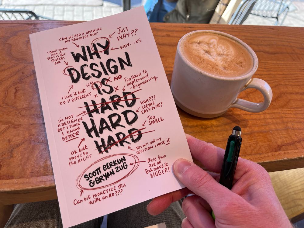 Cover of the book Why Design Is Hard, showing its heavily annotated and humorous design style… alongside a fresh cafe decaf latte 