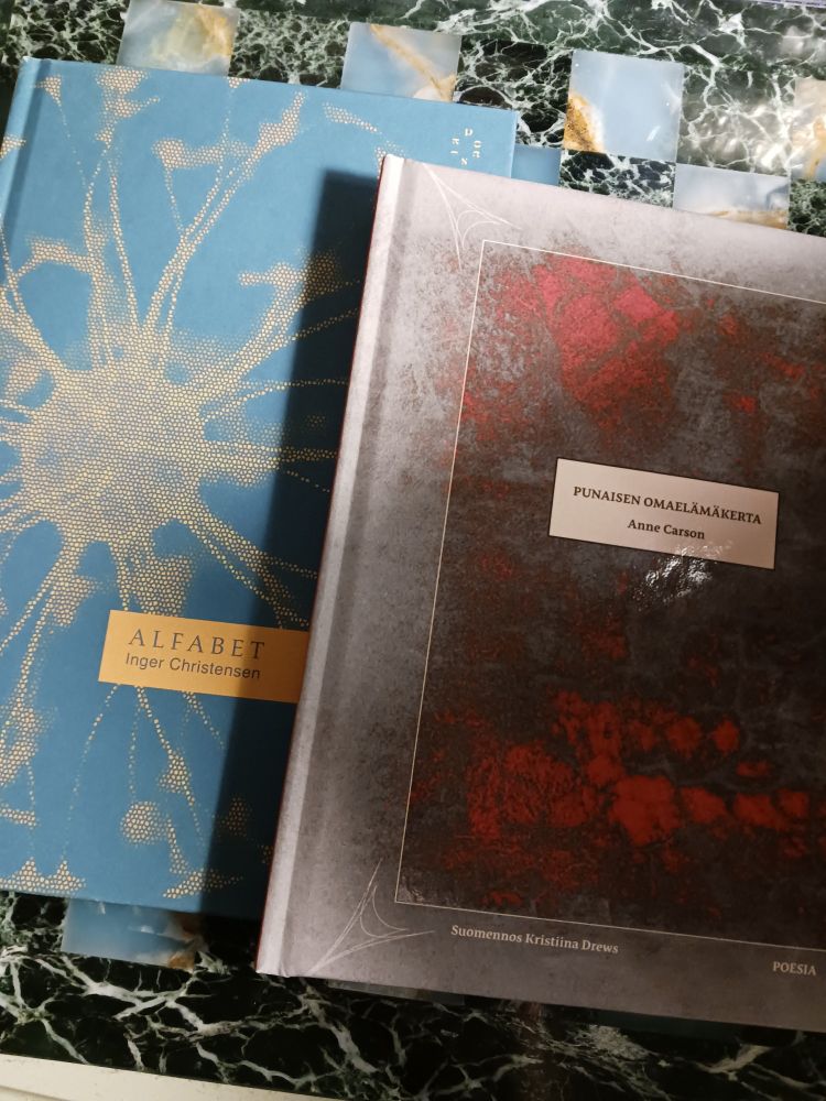Kuvassa on kaksi Poesian kustantamaa kirjaa: Anne Carsonin teos Punaisen omaelämäkerta, jonka on suomentanut Kristiina Drews, ja Inger Christensenin Alfabet, jonka on suomentanut Oscar Rossi.