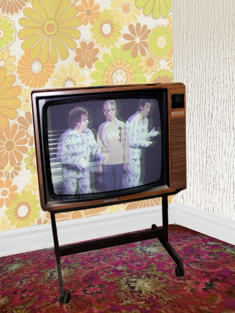 Old TV with ghosting (misaligned duplicate image) with Roy Jay appearing on the Little & Large show 31/12/83. 
Eddie Large is in the same arrow prison outfit as Roy. Syd Little is in a beige jumper with a zig zag pattern.