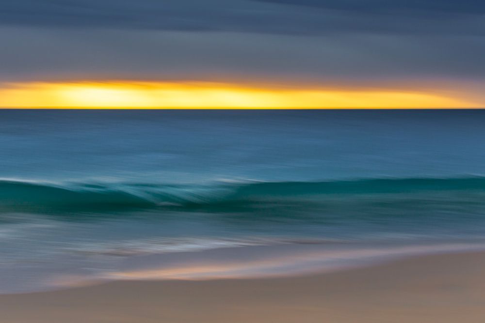 Clean, clear and often translucent, the waves roll in, seemingly out of nowhere, under a stormy sunset sky.