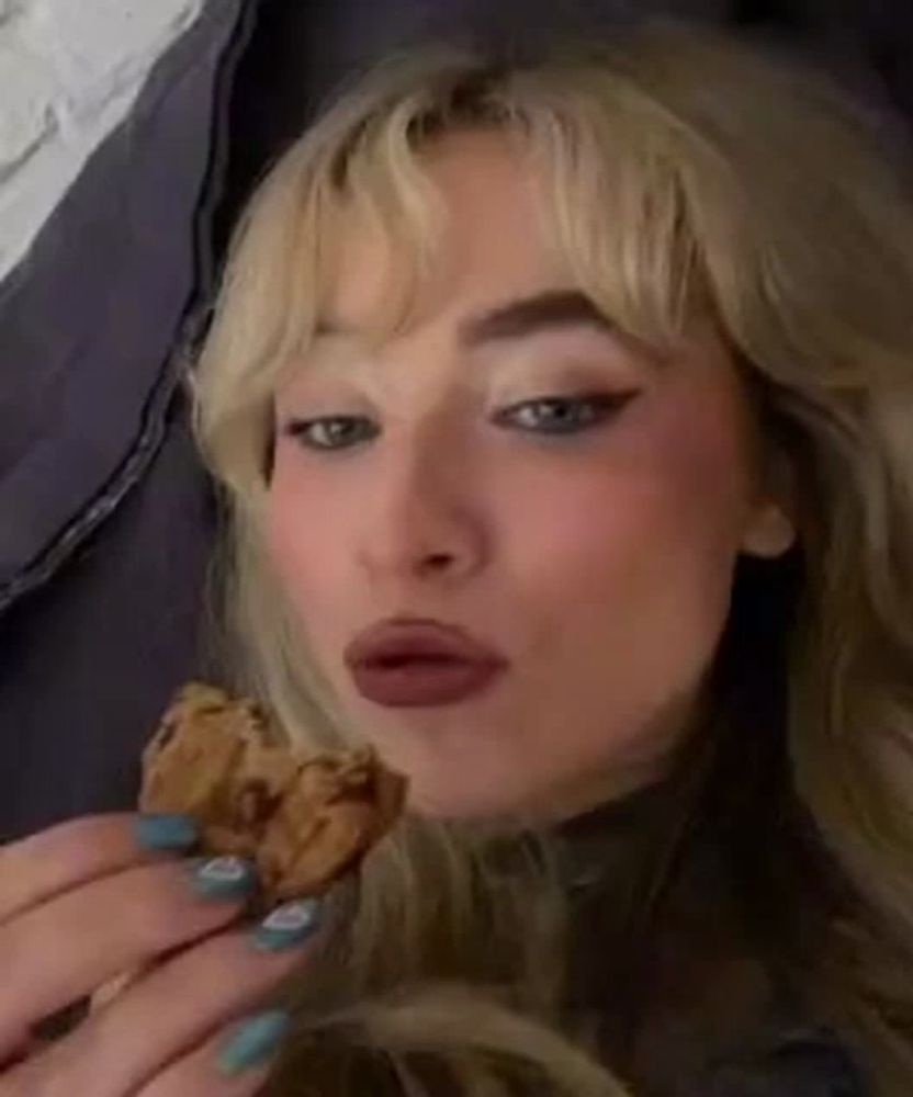 a close up of a woman eating a cookie while laying on a bed .