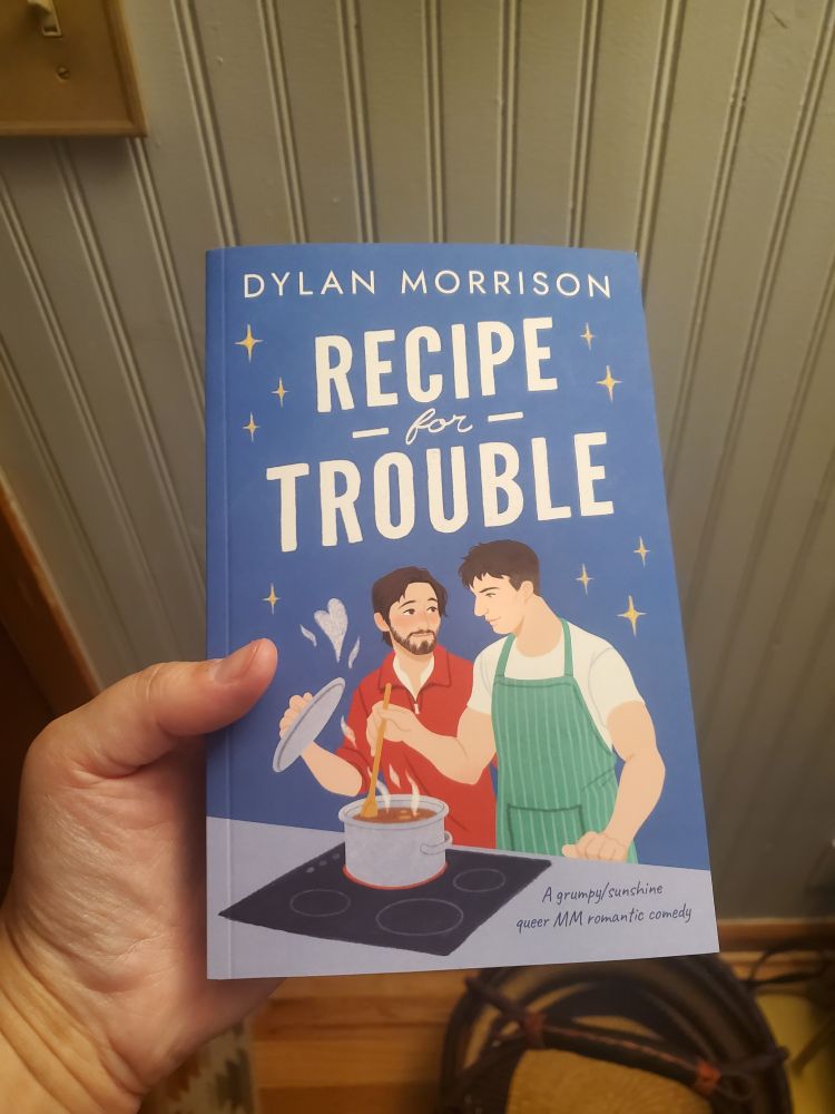 zara's disembodied hand holds a brand-spanking-new paperback copy of dylan morrison's ✨️recipe for trouble✨️
