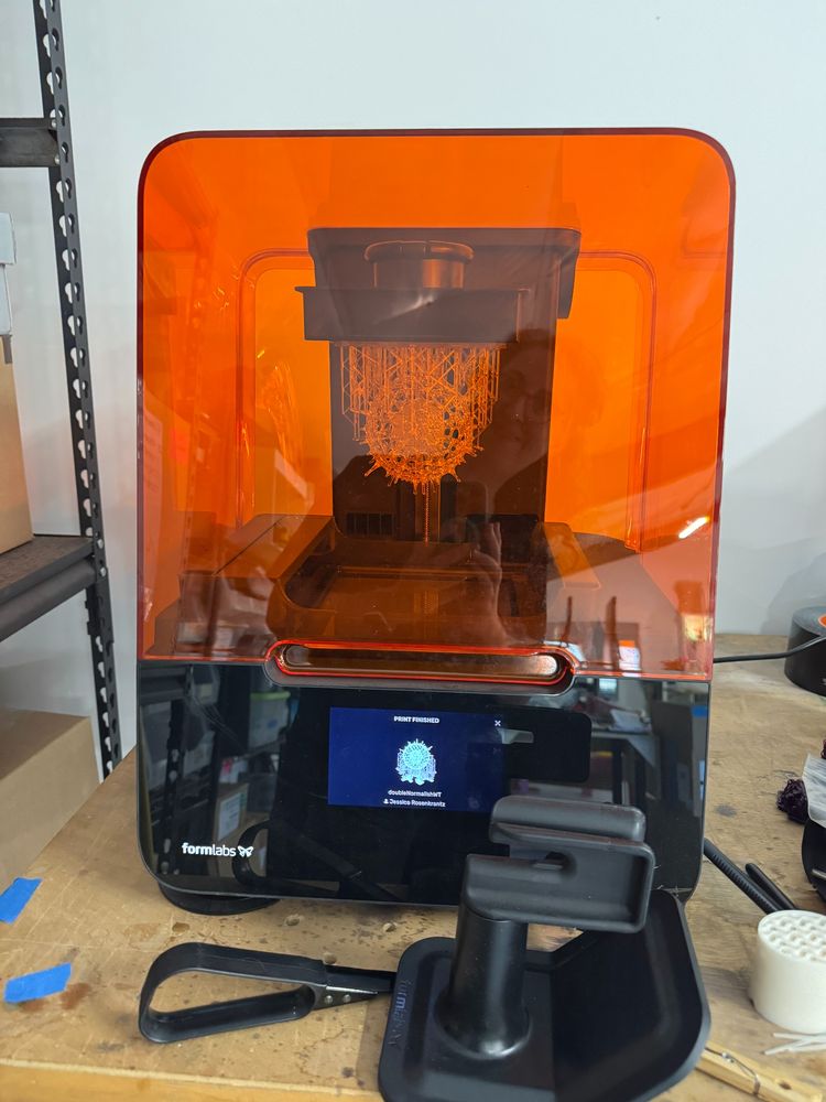form 3 printer with a finished radiolarian hanging from the build plate inside it's orange case