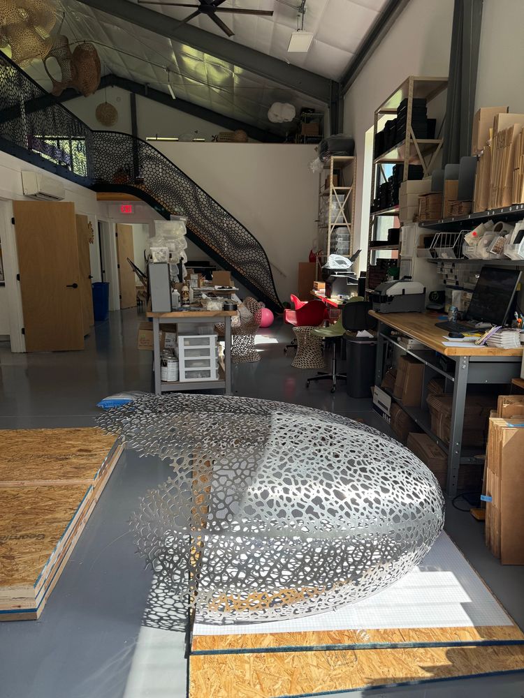 The hyphae lantern rests on a piece of OSB plywood on the floor as sunlight hits it sparkling