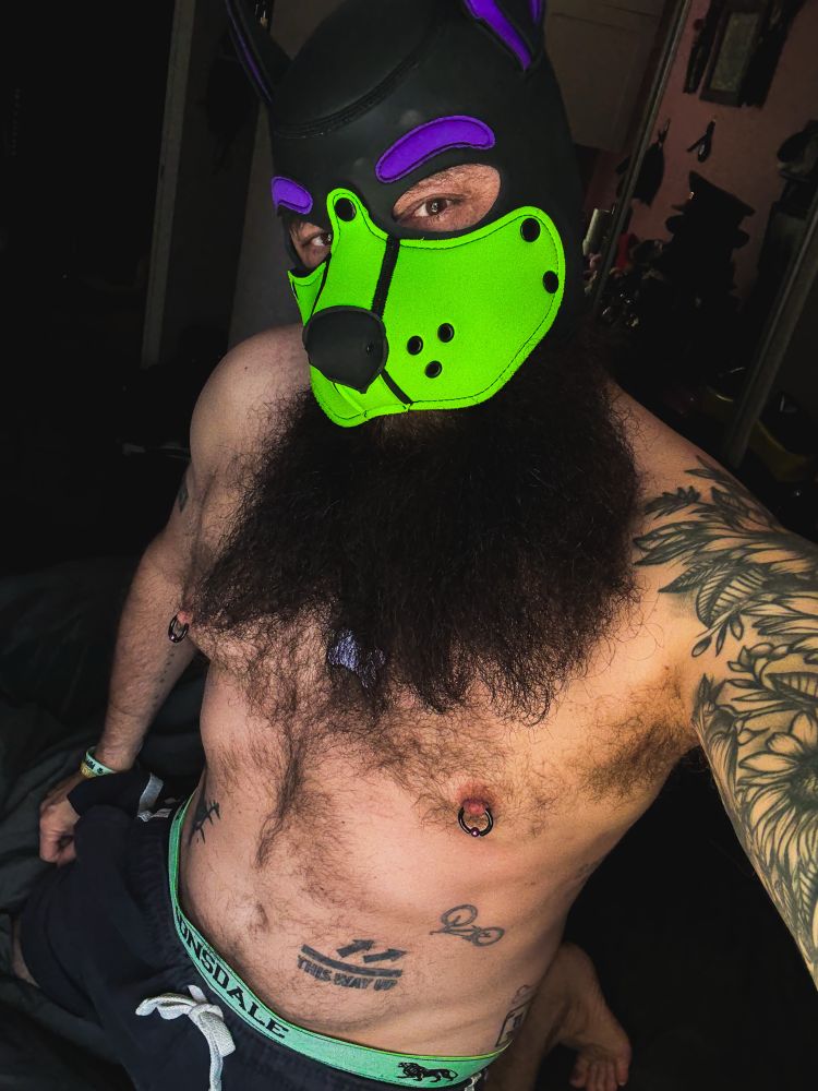 A shirtless purple and green pup with a great big beard 