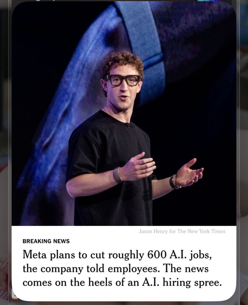 Mark Zuckerberg wearing smart glasses and a black shirt is speaking on stage, with a headline about Meta cutting roughly 600 AI jobs.
