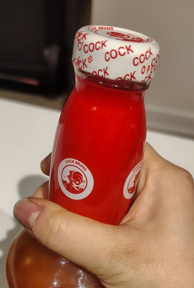 Photo of the top of a bottle of sweet chili sauce with the brand, "cock", emblazoned over the tip
